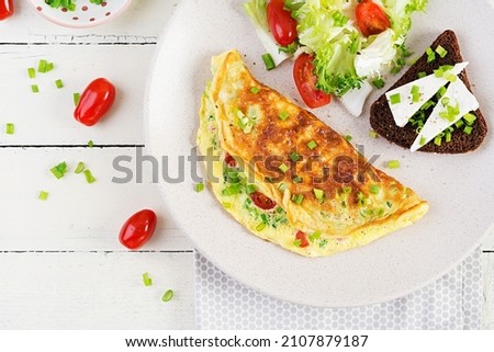 Breakfast. Omelette with tomatoes, cheese, green onions and sandwich with feta cheese.  Frittata - italian omelet. Top view, above Stock fotó © 