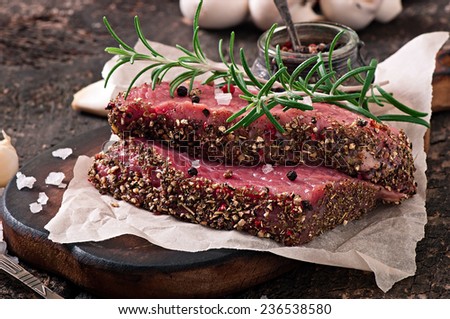 Raw beef steak with spices and a sprig of rosemary