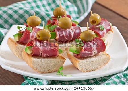 Snack on toast with ham, avocado and olives