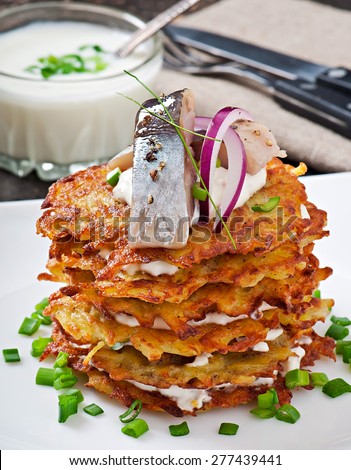 Fried potato pancakes with herring on the old wooden background
