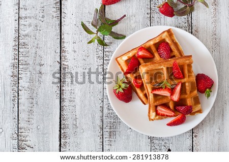 Belgium waffles with strawberries and mint  on white plate. Top view