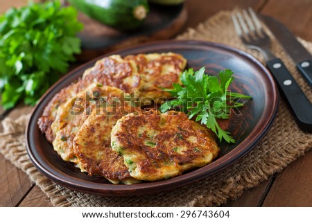 Zucchini pancakes with parsley on a wooden table.