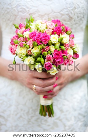 Closeup view of a bride holding bouquet of roses