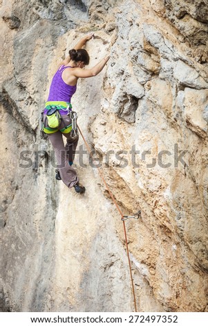 Young female rock climber on overhanging cliff