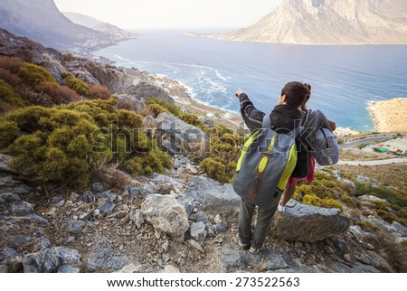 Young couple of tourists looking down at coast, man pointing at something