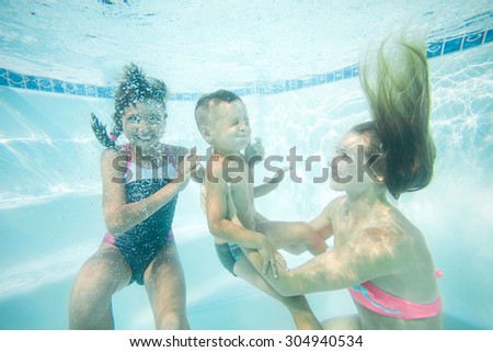 Happy family swimming underwater. Mother, son and daughter having having fun in pool.