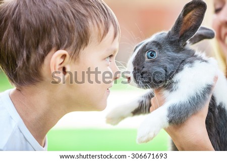 Little boy looking at pet rabbit in mom\'s hands