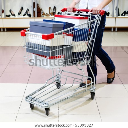 Woman pushing a shopping cart full of shoe boxes in a shoe store. Lower half body view.