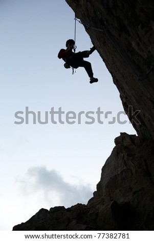 Silhouette of rock climber against sky background