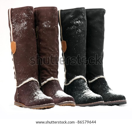 Two pairs of knee-high female boots covered with snow