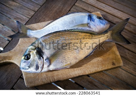 Delicious fresh sea bream fish on wooden kitchen board. Culinary healthy cooking.