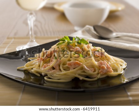 spaghetti with cream and salmon on black plate close up