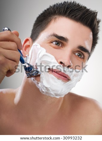Young Man shaving with razor close up