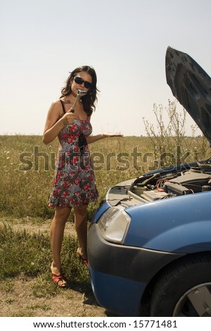 young woman with a wrench trying to fix a broken car