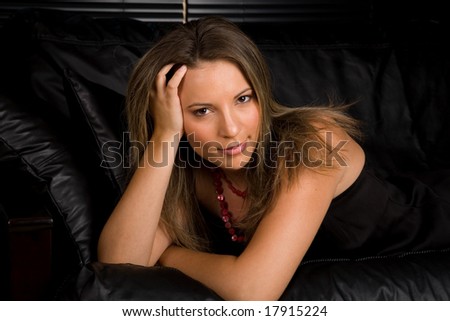Beautiful Young Woman Lying on Black Couch