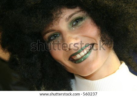 Smiling girl in afro-wig and hard makeup on her way to a party or masquerade.