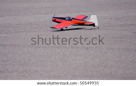 red radio controlled gas powered recreational airplane sitting in parking lot