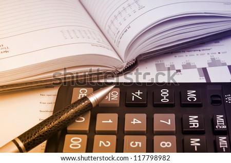 Diary, pen and calculator over annual report