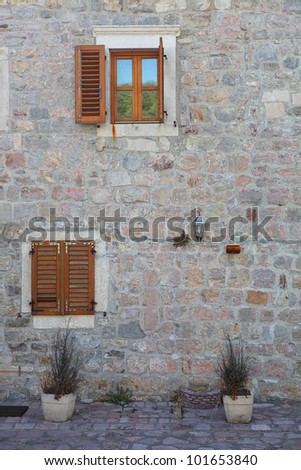 Exterior, windows with red wooden shutters in a rock wall