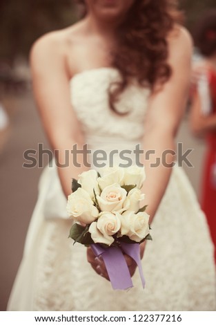 Bride in a white dress in summer green park with a bouquet in hand