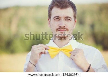 stylish young man in a park in the bow tie