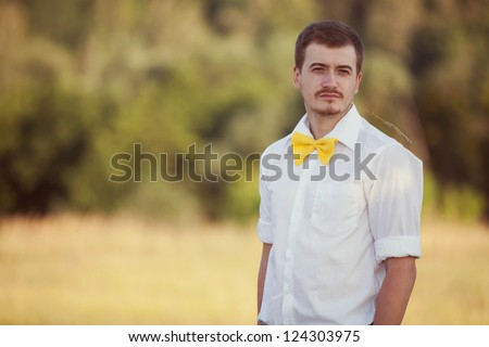 stylish young man in a park in the bow tie