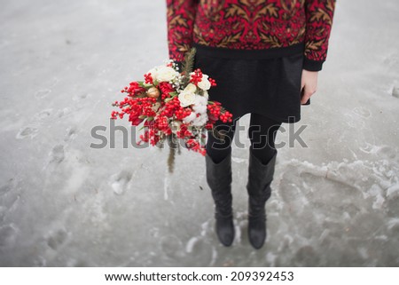 beautiful girl in the park in winter,  with a bouquet of red flowers