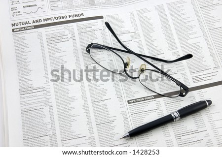 Glasses, pen over mutual funds data on newspaper