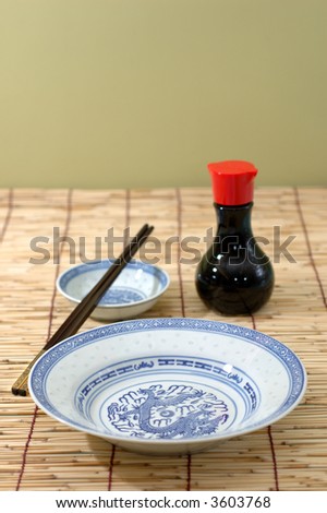 Chinese plate, chopsticks and soya sauce bottle on bamboo background