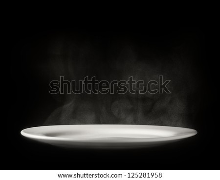 Photo of white plate with steam on black background