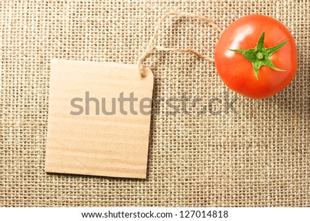 Photo of tomato vegetable and price tag on sacking background texture
