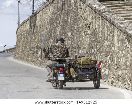 Motorcyclists, dressed in camouflage and equipped with gun drives through the road of an Italian city
