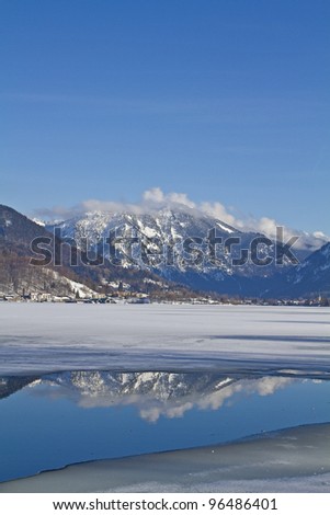 Hole in the ice at the Tegernsee with mirror image of the Wallberg Mountain