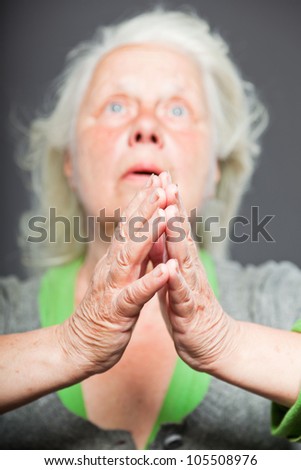 Senior woman white grey hair doing spiritual poses. Expressive face and hands. Studio shot isolated on grey background.