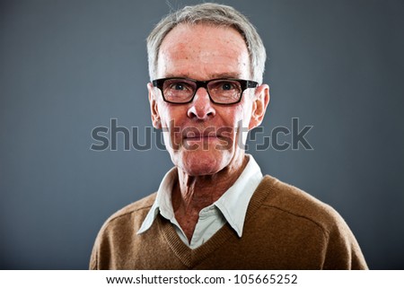 Expressive good looking senior man wearing glasses against grey wall ...