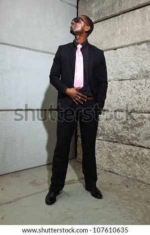 Cool black american man in dark suit wearing sunglasses. Fashion shot in urban setting.
