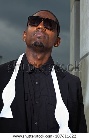 Cool black american man in dark suit wearing sunglasses. Fashion shot in urban setting.