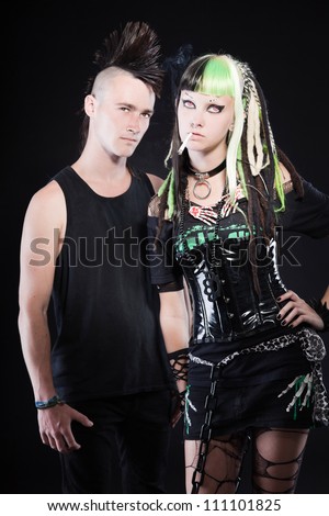 Couple of cyber punk girl with green blond hair and punk man with mohawk haircut. Isolated on black background. Studio shot.