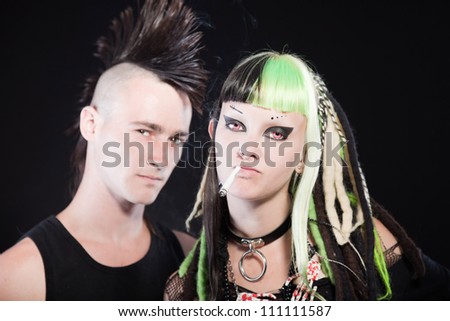 Couple of cyber punk girl with green blond hair and punk man with mohawk haircut. Isolated on black background. Studio shot.