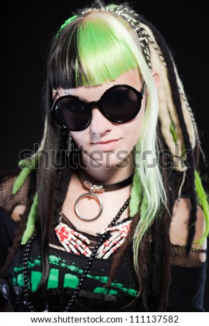Cyber punk girl with green blond hair and red eyes isolated on black background. Wearing black sunglasses. Expressive face. Studio shot.
