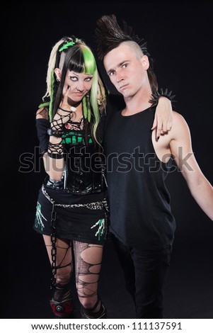 Couple of cyber punk girl with green blond hair and punk man with mohawk haircut. Expressive faces. Isolated on black background. Studio shot.