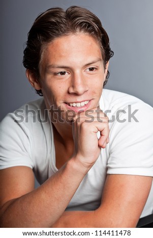 Teenage boy with brown hair and eyes. Wearing white t-shirt. Good looking. Casual wear. Expressions. Studio closeup portrait isolated on grey background.