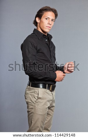 Teenage boy with brown hair and eyes. Wearing black shirt and khaki pants. Good looking. Casual wear. Expressions. Studio portrait isolated on grey background.