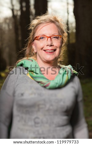 Happy healthy senior woman enjoying nature in forest.