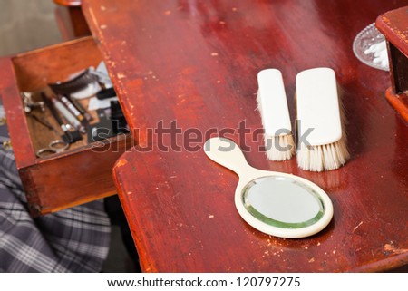 Antique mirror with two brushes on old wooden make-up table.