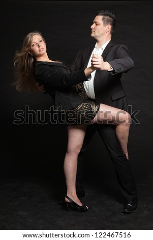 Dancing couple in love. Studio shot against black.