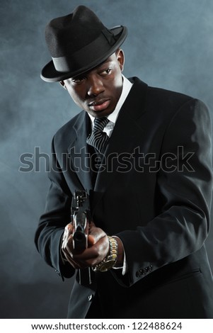 Black american mafia gangster man in suit with gun.