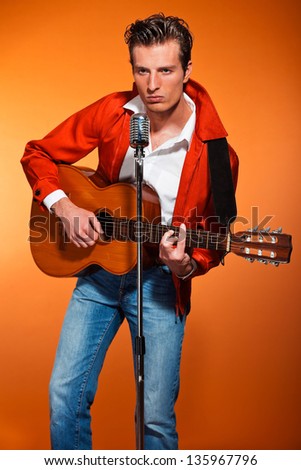 Retro fifties rock and roll singer playing acoustic guitar. Studio shot.