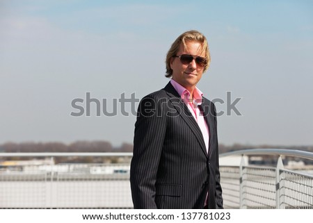 Business man with sunglasses outdoor on rooftop of office building.