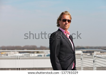 Business man with sunglasses outdoor on rooftop of office building.